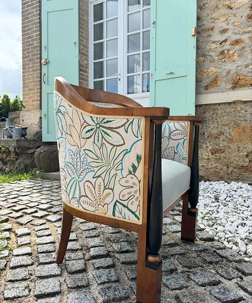 Fauteuil ancien restauré à motifs floraux devant une façade pastel