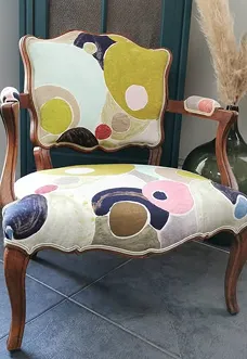 Fauteuil ancien retapissé avec un tissu coloré